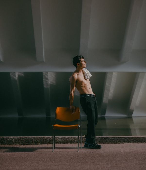 Man focused on a stretching pose in a calm, minimalist gym setting.